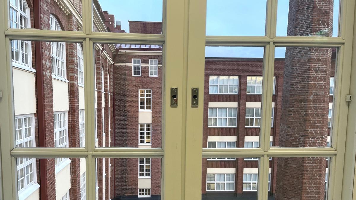 Kuvassa on ikkuna ja näkymää vanhasta tehdasrakennuksen pihasta.